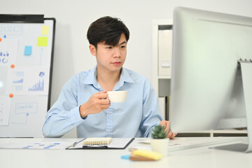 Obraz na płótnie Canvas Image of asian businessman drinking coffee and working on marketing project at modern office