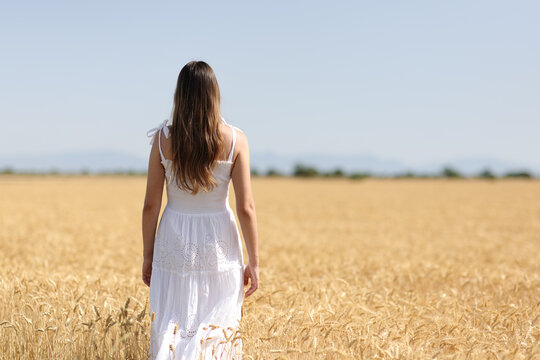 Woman in white dress walks in a field