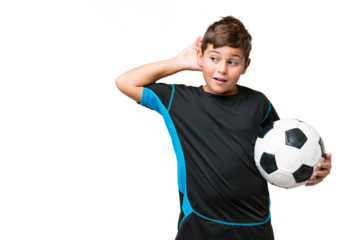 Little caucasian football player kid over isolated chroma key background listening to something by putting hand on the ear