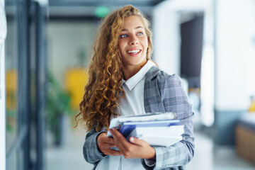 Fototapeta premium Young business woman standing against office interior background. People, business, freelance, work concept 