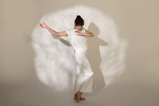 Contemporary dancer dancing against spotlight on brown background
