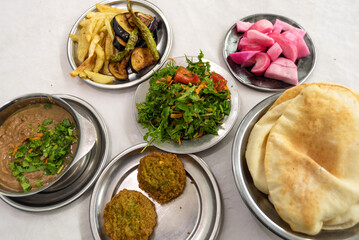 A table prepared with typical Egyptian street food of Fuul and Falafel with Salad, Pickles and Local Bread, healthy and cheap food all over Egypt.
