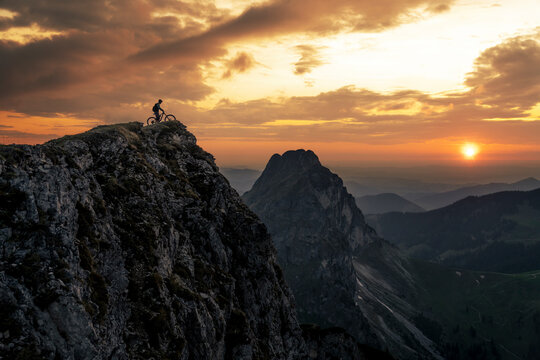 Man with bike on top of mountain at sunset