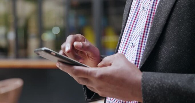 Close up of one black businessman using mobile phone typing on smartphone in the urban place