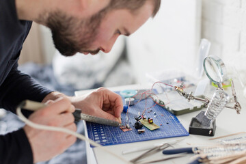 Engineer soldering circuit board at workshop