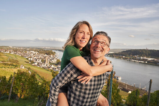 Happy mature man giving piggy back ride to woman on sunny day