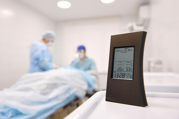 Digital clock on table with doctors in background