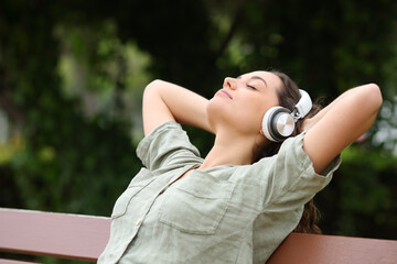 Woman resting listening to music on a bench in a park