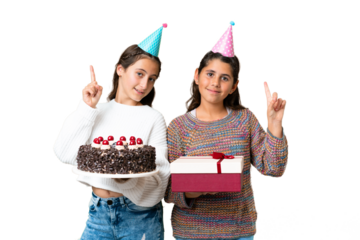 Friends girls holding gift and a birthday cake over isolated chroma key background showing and lifting a finger in sign of the best