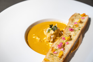 Close up to Garlic Bread with Creamy TomYamKung Soup on white dish in studio light, decorated with flower petal on it.
