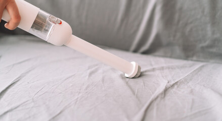 Cleaning lady vacuums the bed from dust with manual vacuum cleaner. © Anastassiya 