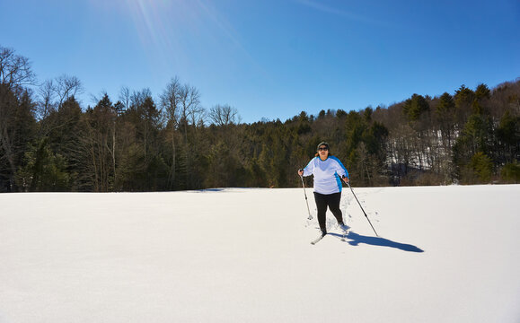 Woman cross country skiing through field, Braintree, Vermont, USA