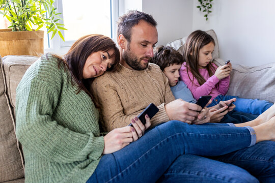 Man and woman with children using smart phone at home