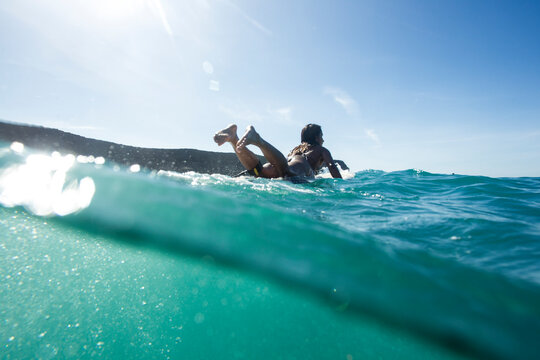 A girl paddles on her longboard during a surf session