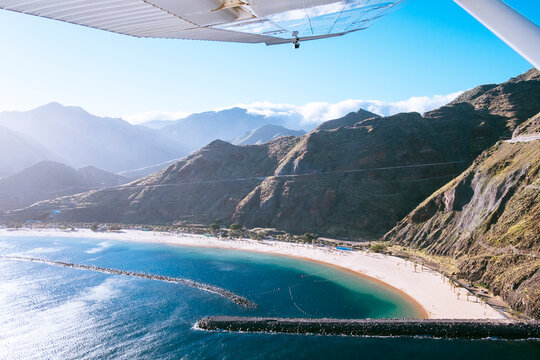 Aerial view of a white sand beach located at the base of a cliff