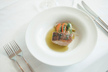 Piece of meat with vegetables on plate against white table, La Rioja, Pamplona, Spain