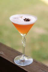 Orange alcoholic cocktail with lemonade, champagne or Martini, with foam and decorated with star anise.