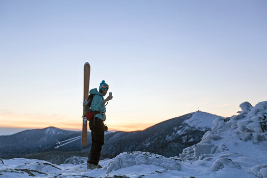 Female skier at summit of Burnt Mountain at sunset