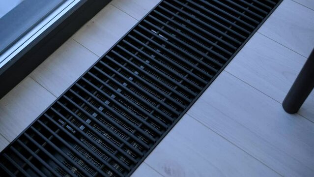 Protective radiator grille built into the floor for heating panoramic windows. Heating grid with ventilation by the floor in hardwood flooring