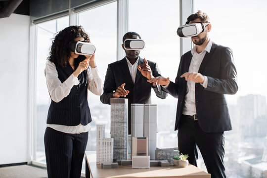 VR, business meeting conference. Multiethnic male and female business people wearing virtual reality headsets, touching air and gesturing at the office, working with new project or program.