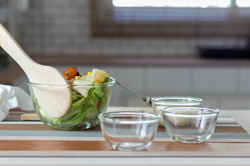 young woman is making salad from vegetables she has prepared on table in her home kitchen to get salad that is clean and safe because ingredients are carefully selected. healthy food preparation ideas