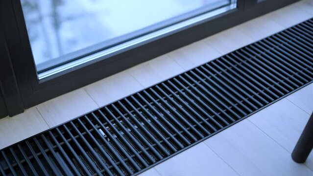 Protective radiator grille built into the floor for heating panoramic windows. Heating grid with ventilation by the floor in hardwood flooring