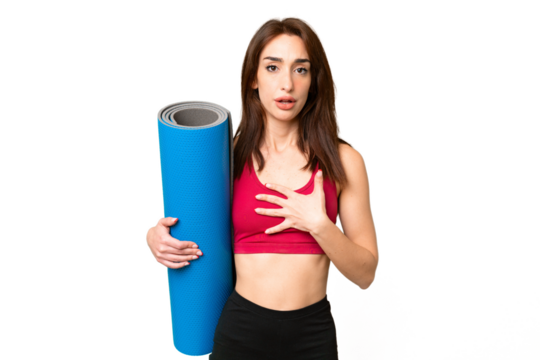 Young sport caucasian woman going to yoga classes while holding a mat over isolated chroma key background surprised and shocked while looking right