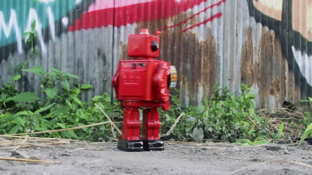 vintage red robot toy marching and spinning with a corrugated iron background 