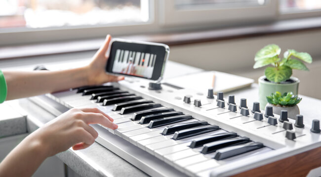 The child learns to play the piano with a smartphone, online music lesson.
