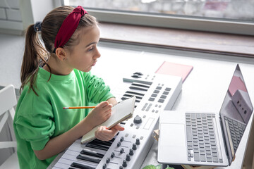 A girl learns to play the piano with a teacher online, remote learning music.