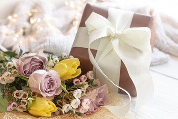 Spring composition with flowers and a gift box on a blurred background.