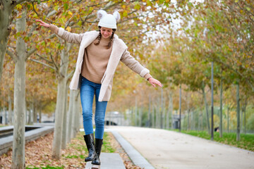 Preteen girl with two braids walking on balance beam outdoors in autumn.