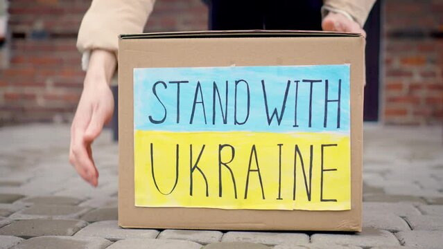 Ukrainian woman refugee takes from responsible volunteers cardboard box with donated food and humanitarian aid leaving near her new home in foreign country slow motion. Help Ukraine in war with