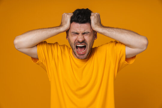 Young white man screaming and grabbing his head in panic