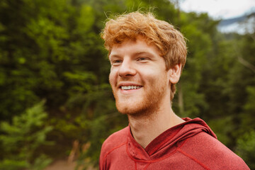 Cheerful redhead man smiling while standing outdoors