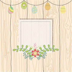 Photo or text frame with flowers on a wooden background with a garland of Easter eggs
