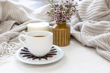 Home composition with a cup of coffee, a candle and a bouquet of flowers.