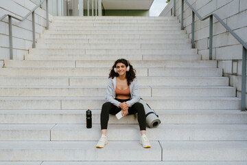 Young woman using gadgets while sitting on stairs