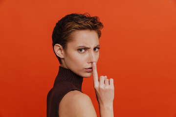 Young beautiful serious woman showing silence gesture with finger