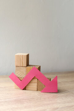 The concept of economic collapse and the collapse of the stock exchange. Wooden blocks and a graph arrow pointing down.
