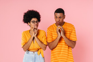 Cunning african american couple clasping hands isolated over pink wall