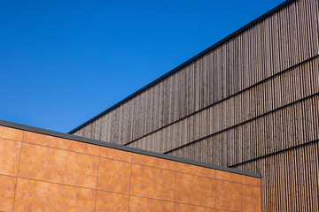 Abstract photo of blue sky, rusty weather resistant steel / corten steel and a wooden wall. Divied into triangles. Anonymous architecture. Vertical shot with copy space.