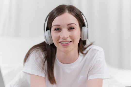 Image of beautiful young woman with headphone resting in bed at bedroom. Lifestyle at home concept.
