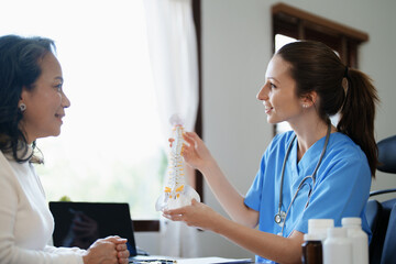 Portrait of a female doctor talking to an elderly patient about herniated disc deterioration from...