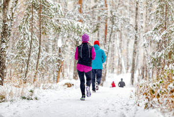 Fototapeta na wymiar athletes runners running winter trail marathon in forest during a snowfall