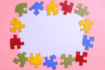 Blank white paper for text space surrounded by colorful puzzle isolated on pink background with copy space. Autism awareness. World Autism Awareness Day. 