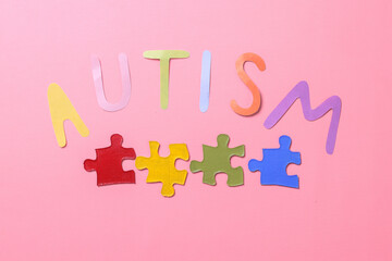 Colorful autism lettering with colorful puzzle isolated on pink background. World Autism Awareness...