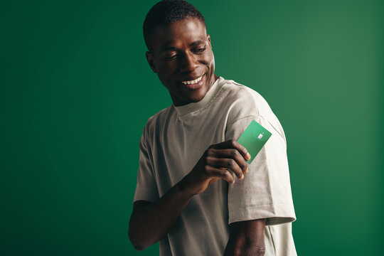 Young people and modern banking: Black male holds a contactless credit card in a studio