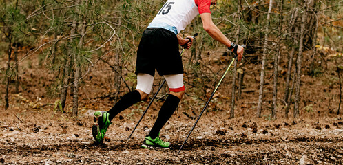 male athlete with trekking poles walk forest trail in skyrunning marathon