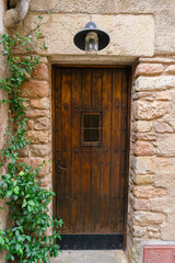 Old wooden door in a stone house with leaves on the facade